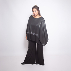 Modelo vistiendo una blusa Idalis de color negro con detalles brillantes y pantalones negros, posando en un fondo blanco.