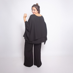 Modelo de espaldas vistiendo una blusa negra Idalis, con pantalones a juego, en un fondo blanco.