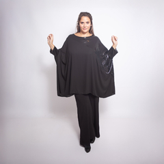 Modelo luciendo una blusa negra Idra con mangas amplias y detalles brillantes, combinada con pantalones oscuros.