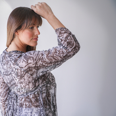 Blusa Iris de diseño elegante con estampado en tonos neutros, vista lateral de una mujer que muestra la prenda.