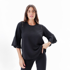 Blusa negra con mangas acampanadas y detalles en los hombros.