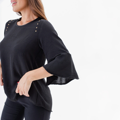 Blusa negra de mujer con mangas acampanadas y detalles metálicos en los hombros.