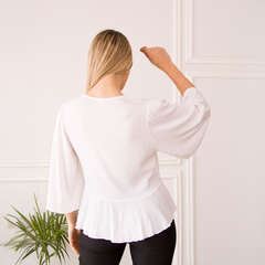 Vista trasera de la blusa Lupe, de color blanco, con mangas amplias y detalles en la parte inferior.