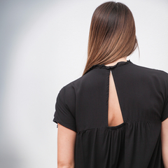 Vista posterior de una blusa negra con detalle de abertura en la parte superior.