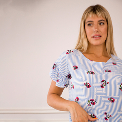 Blusa Nahia de rayas azul con estampado floral en tonos rojos, modelo con mangas rizadas.