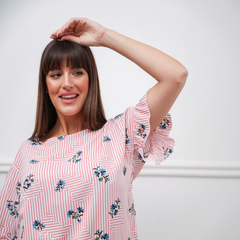 Modelo luciendo una blusa Nahia de rayas rosas con flores bordadas.