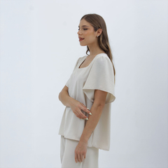 Blusa Nalani de color claro, con mangas anchas y corte cuadrado, vista lateral de una modelo.