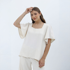 Blusa Nalani de color crema con mangas amplias y escote cuadrado, modelada por una mujer.
