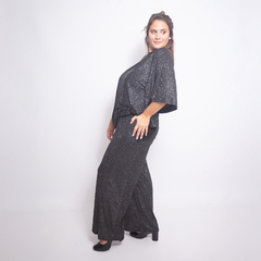 Modelo luciendo la blusa Neus de color negro con brillo, combinada con pantalones anchos y zapatos de tacón.