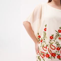 Blusa elegante de color crema con bordados florales en tonos rojos y verdes, ideal para ocasiones especiales.