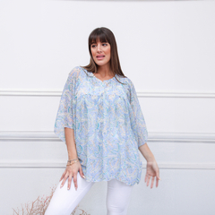 Blusa Siena en color azul claro con estampado de paisley, modelo posando frente a una pared blanca.