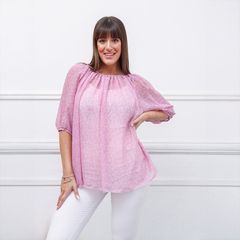 Modelo posando con blusa rosa de manga abullonada, sobre fondo blanco.