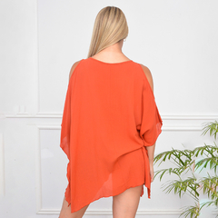 Blusa Taima de color naranja vista desde atrás, con un diseño suelto y mangas abiertas.
