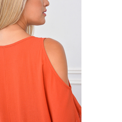 Vista trasera de una mujer usando una blusa naranja sin mangas, mostrando detalles de la prenda.