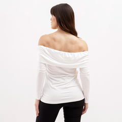 Mujer de espaldas vistiendo una blusa blanca sin mangas con escote de barco, combinada con pantalones negros.