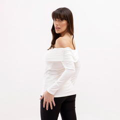 Modelo luciendo una blusa blanca de manga larga con un diseño off-shoulder y fruncidos.