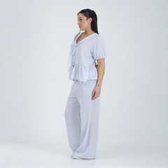 Modelo luciendo la blusa Tulum de rayas con peplum y pantalones a juego en un fondo blanco.