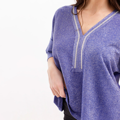 Modelo usando una blusa morada con detalles brillantes y escote en V.