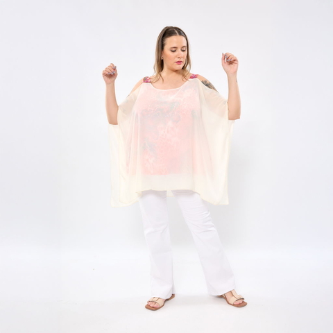 Modelo usando blusa Bella Transfer color clara con diseño suelto y hombros descubiertos, combinada con pantalones blancos y sandalias beige