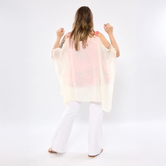 Vista trasera de una mujer con blusa elegante Bella Transfer de tela traslúcida color crema y pantalones blancos
