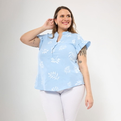Modelo con blusa Ligura azul claro con estampado de hojas blancas y pantalones blancos