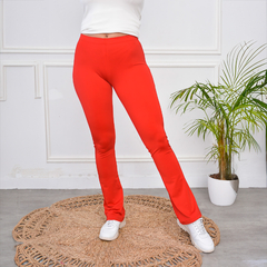 Calza Brisa de color rojo, ajustada al cuerpo, luciendo en un ambiente moderno con planta decorativa.