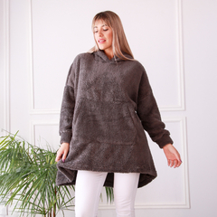 Buzo Maxi Oli en color gris, con capucha y diseño cómodo, combinado con pantalones blancos y un fondo neutro.