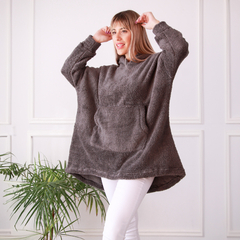 Buzo Maxi Oli en color gris, con un diseño amplio y capucha, modelado por una mujer en un ambiente luminoso.