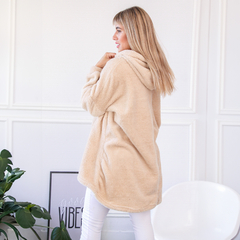 Buzo Maxi Oli color beige, con capucha, modelo de mujer de perfil, en un ambiente luminoso.