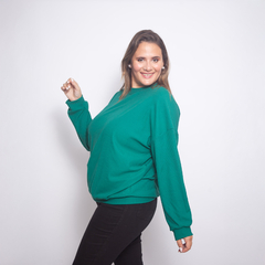 Buzo Suiza de color verde, modelo sonriente posando con una mano levantada.