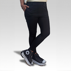 Pantalones calza negros ajustados con bolsillos, combinados con zapatillas negras y blancas.