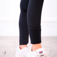 Pantalones deportivos negros ajustados con detalles en el dobladillo, combinados con zapatillas blancas.