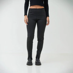Pantalones ajustados oscuros con detalles en la parte inferior, combinados con un top negro.