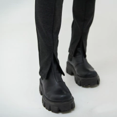 Pantalones oscuros con abertura en los laterales y botas negras de suela gruesa.