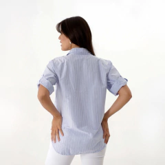 Vista trasera de una camisa Benna de rayas azul, usada por una mujer con cabello largo.
