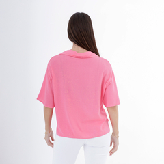 Vista posterior de una mujer usando una camisa clavel de color rosa.