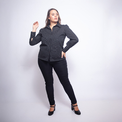 Mujer con camisa negra de rayas blancas Lazio, pantalones ajustados negros y zapatos de tacón negro, posando en fondo blanco