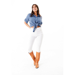 Modelo usando una camisa azul atada en la cintura, con pantalones blancos y botas marrones.