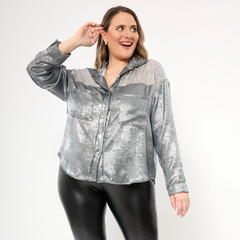 Camisa Castilla plateada con detalles brillantes, manga larga y cierre de botones, combinada con pantalones de cuero negro.