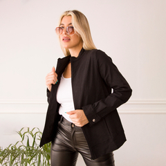 Campera Ada negra, modelo femenino con gafas de sol, posando en un ambiente minimalista.