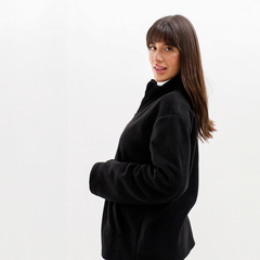 Modelo usando una campera negra tipo polar Ersa, de perfil, con fondo blanco.