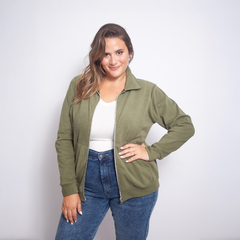 Modelo usando una campera Jolie de color verde oliva, con una camiseta blanca y jeans, sonriendo hacia la cámara.