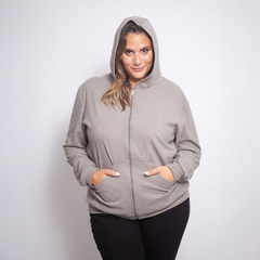 Modelo usando una campera gris con capucha y cierre frontal, de estilo casual.