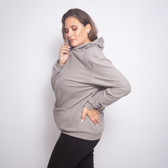 Mujer con campera Kala gris, posando de perfil y sonriendo, con las manos en los bolsillos.