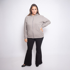 Modelo usando una campera gris con capucha, combinada con pantalones oscuros y zapatos negros.