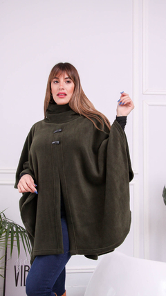 Capa Marano de color verde oliva, con diseño de poncho, presentada por una mujer en un ambiente moderno.