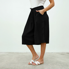 Pantalones Capri Dayak de color negro con bolsillo y cintura elástica, modelo femenino.