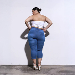 Mujer de espaldas usando un top blanco y jeans ajustados azules, mostrando un look moderno y elegante.