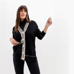 Cardigan Cailin negro con detalles en beige, modelo posando de pie, con un look elegante.