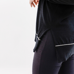 Cardigan negro Cailin con detalles en blanco, visto de costado, combinado con pantalones oscuros.